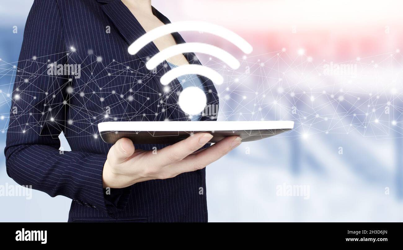 Wi Fi wireless concept. Hand hold white tablet with digital hologram Wi Fi sign on light blurred background. Free WiFi network signal technology inter Stock Photo