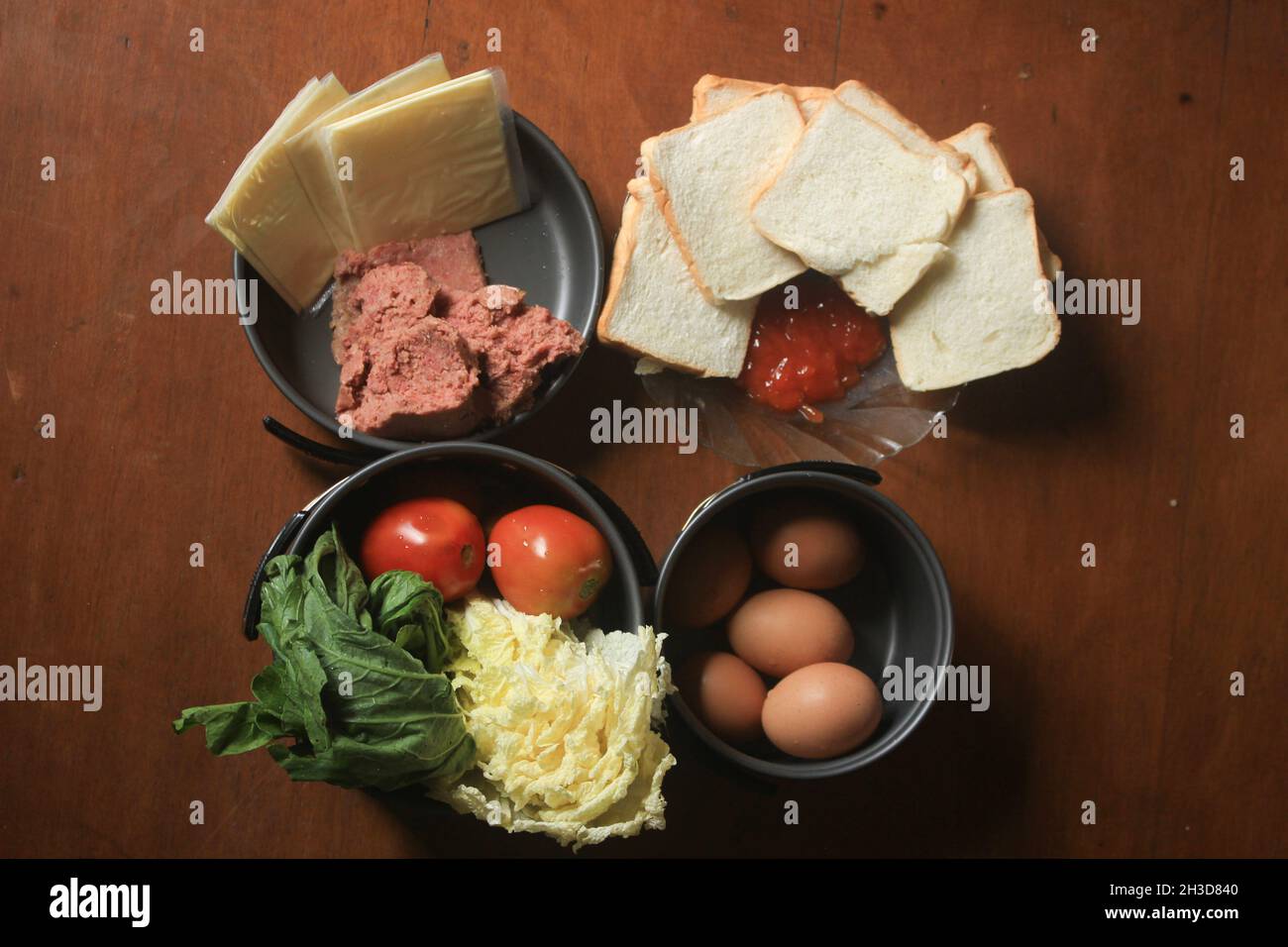 a healthy diet consisting of minced beef, sliced fragrant white bread, sauce, fresh chicken eggs, cheese, mustard greens, and tomatoes. Stock Photo