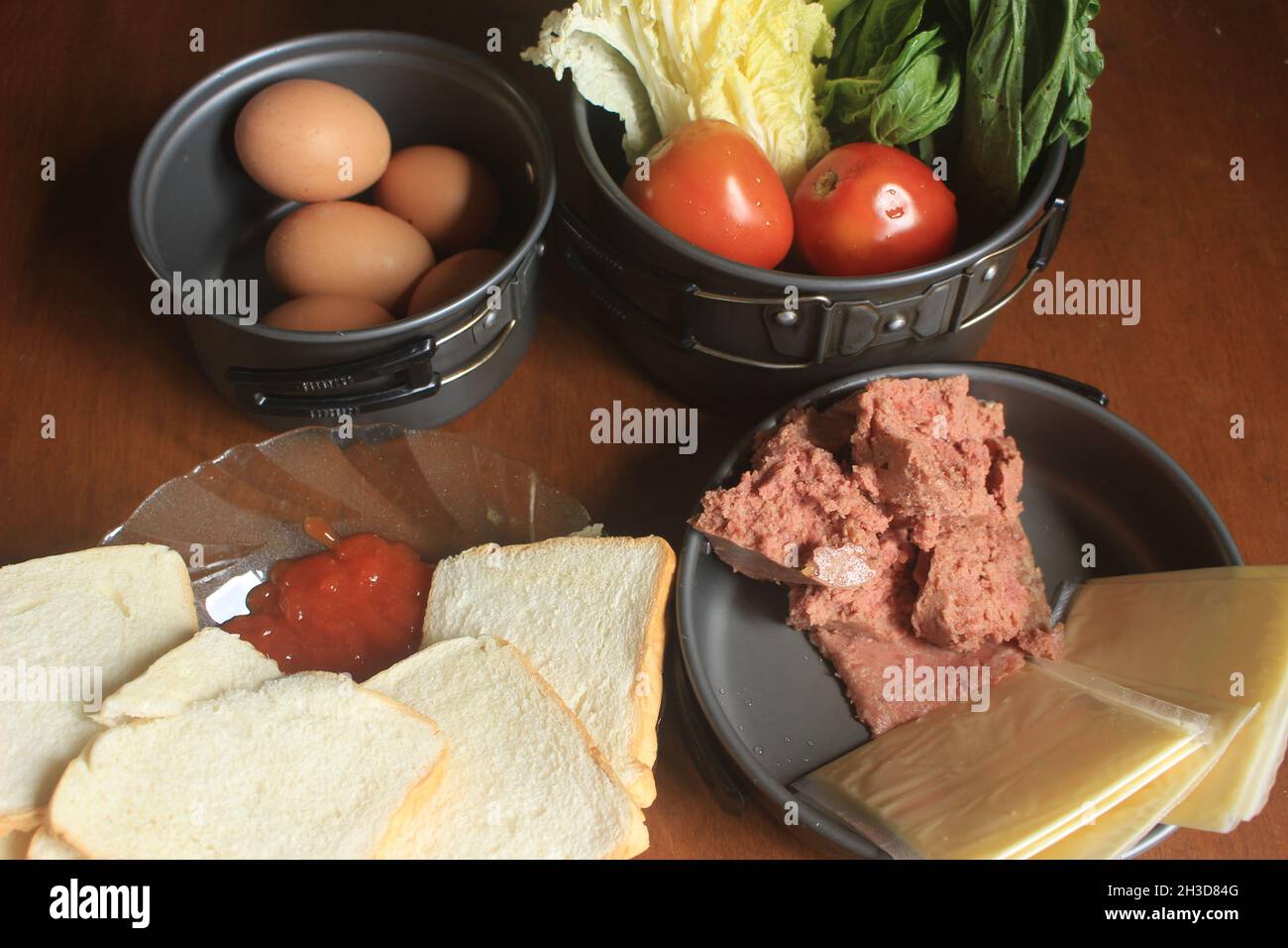 a healthy diet consisting of minced beef, sliced fragrant white bread, sauce, fresh chicken eggs, cheese, mustard greens, and tomatoes. Stock Photo
