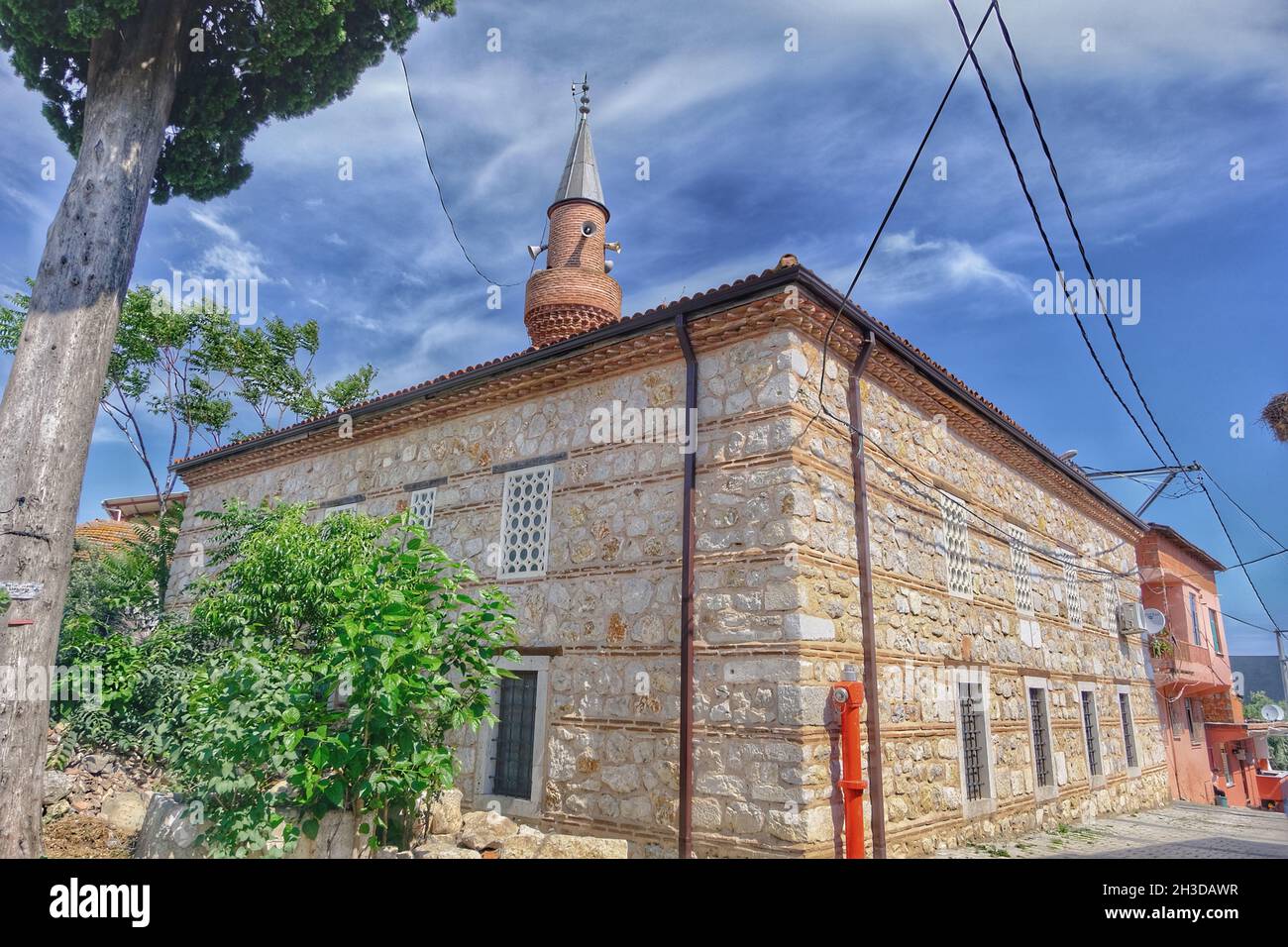 masjid or mosque and its minaret extend to blue and magnificent sky in golyazi (uluabat) bursa with bricks wall together with red fire estinguisher Stock Photo