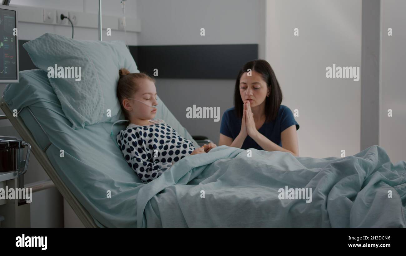 Sick daughter sleeping after recovery surgery while worried mother ...