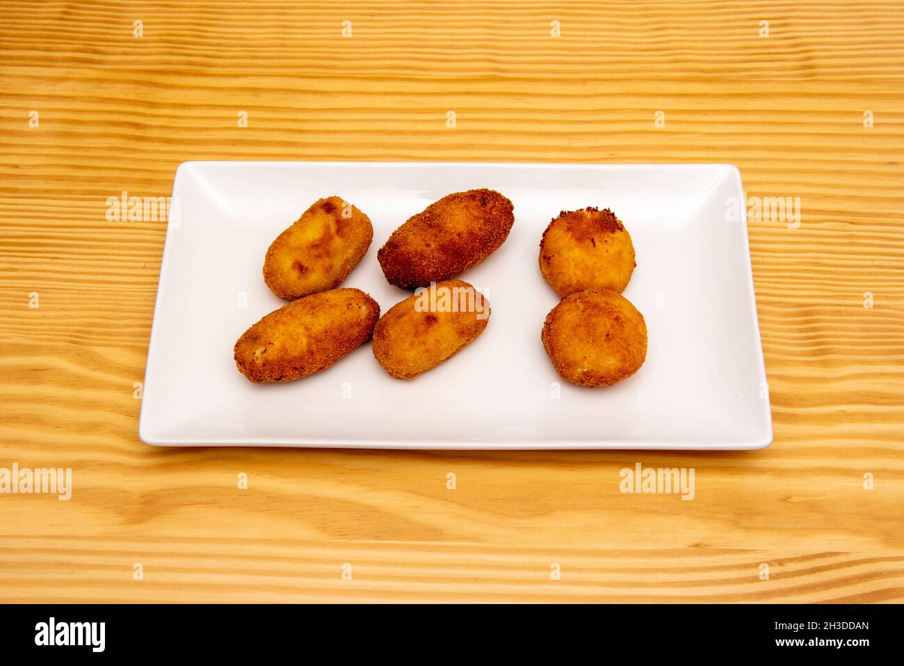 Serrano ham croquettes portion fried in olive oil on a white porcelain