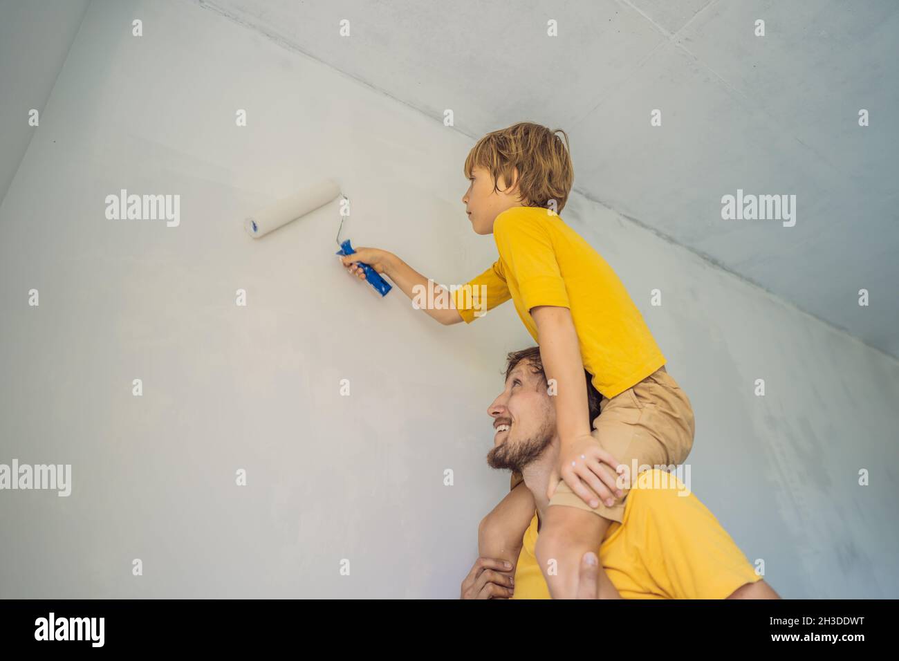 Father and son painting a wall in their home do it in the course of ...