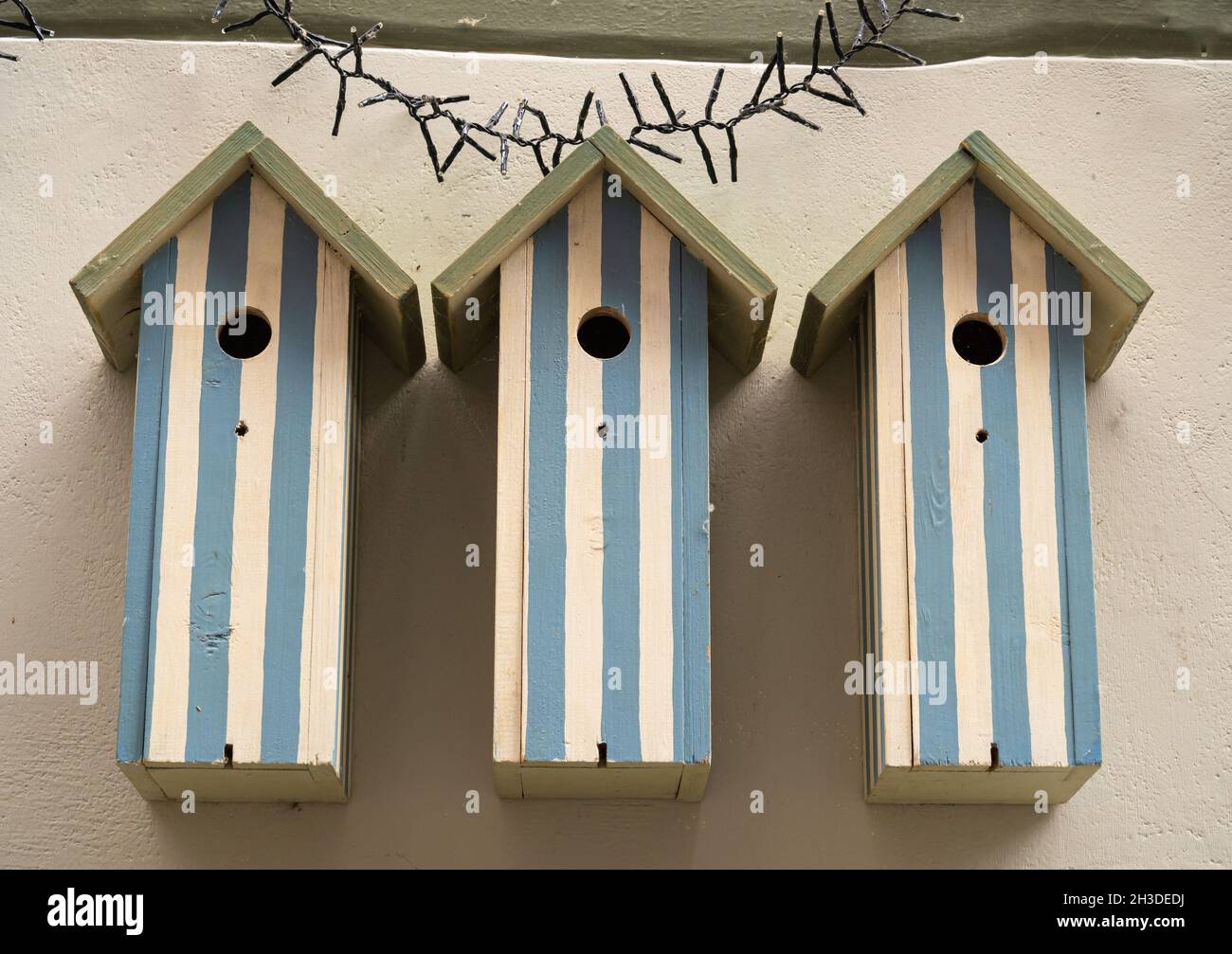 Three wooden white and blue birdhouses on the wall Stock Photo