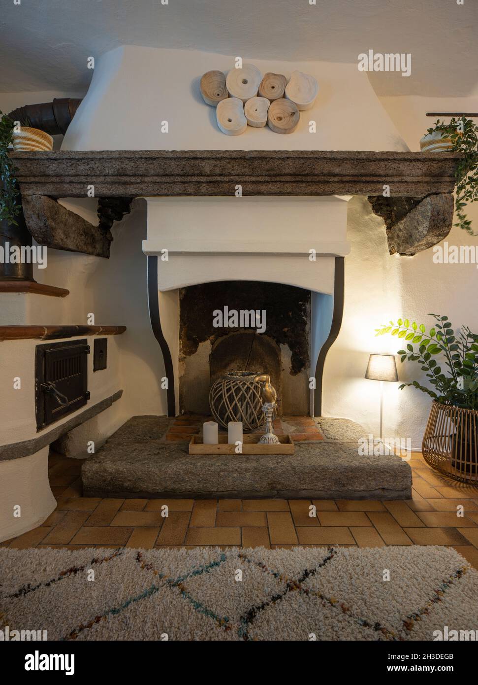 Front view of a fireplace in the living room of a mountain house. Tiles and a carpet on the floor. Nobody inside Stock Photo