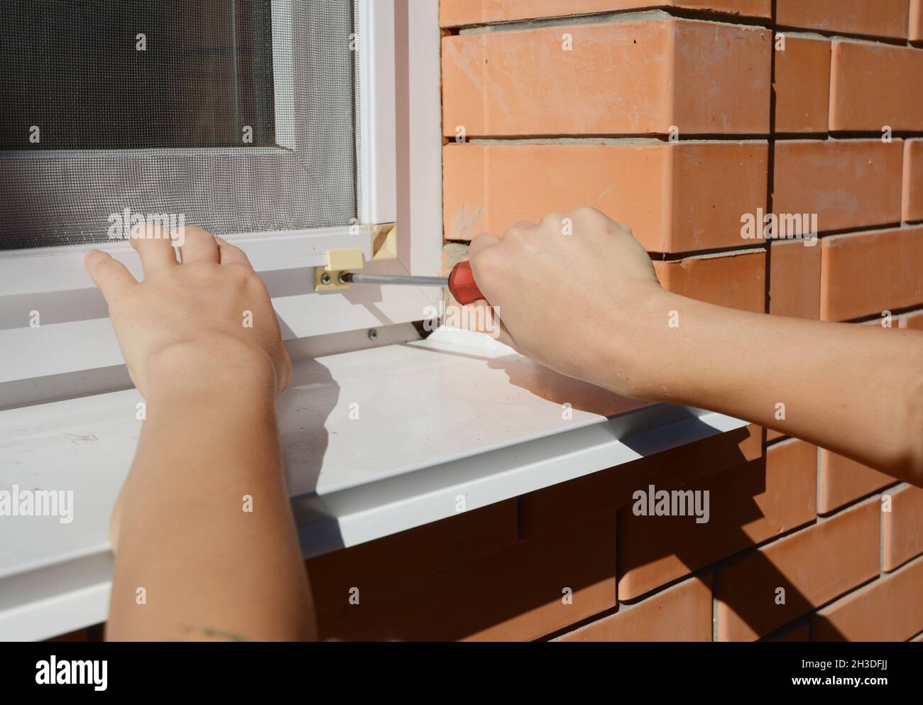 Worker hands installing mosquito net,  mosquito wire screen on  house window. Stock Photo