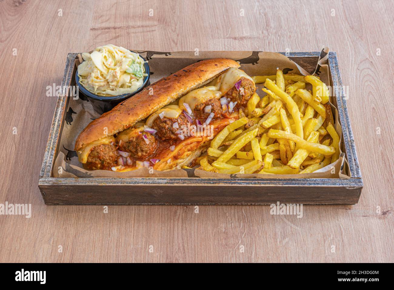 meatloaf hot dog with tomato and melted cheese, pieces of raw red onion and side of French fries