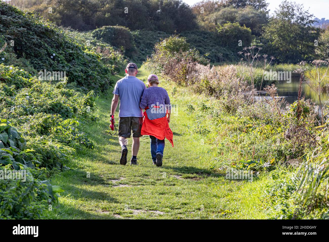 A couple walking along a rural riverside footpath Stock Photo