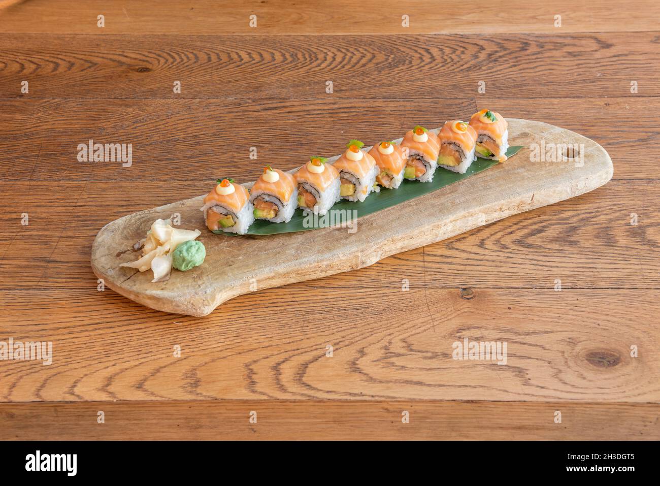 https://c8.alamy.com/comp/2H3DGT5/uramaki-sushi-stuffed-with-salmon-with-avocado-nori-seaweed-and-covered-by-norwegian-salmon-on-japanese-rice-and-banana-leaf-with-wasabi-with-ginseng-2H3DGT5.jpg