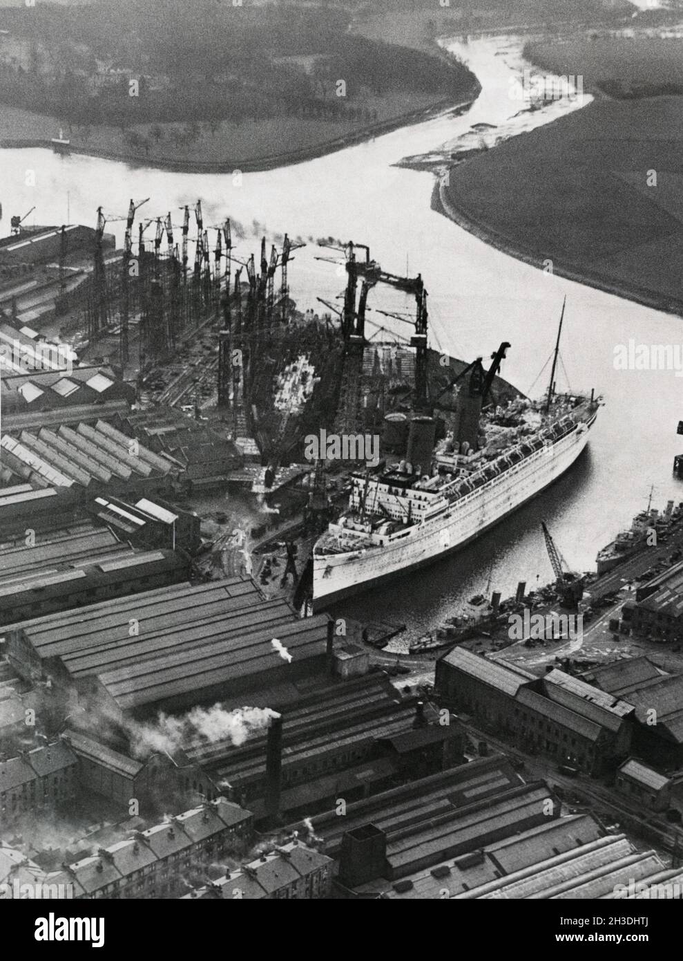 Dockyard in the 1930s. John Brown and company at Clydebank in Glasgow. The company built the famous cruise ships RMS Lusitania, HMS Hood, HMS Repulse, RMS Queen Mary, RMS Queen Elizabeth and Queen Elizabeth 2. Picture shows the ship The Empress of Britain and in the middle the first lower decks om the ship RMS Queen Mary being built. A work that started in december 1930. The ship was launched 1934. Picture taken 1931. Stock Photo