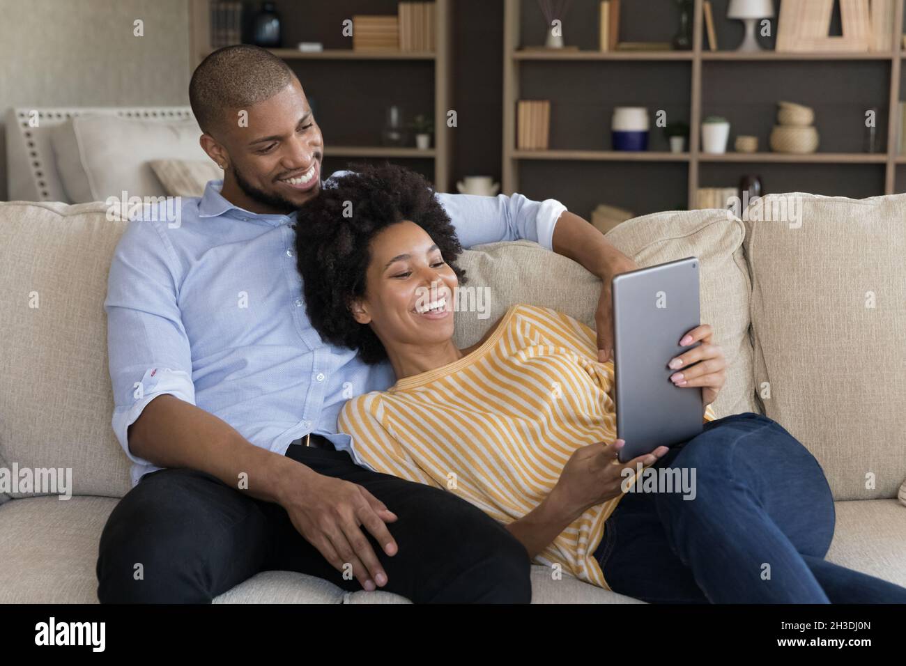Relaxed smiling millennial mixed race couple using tablet. Stock Photo