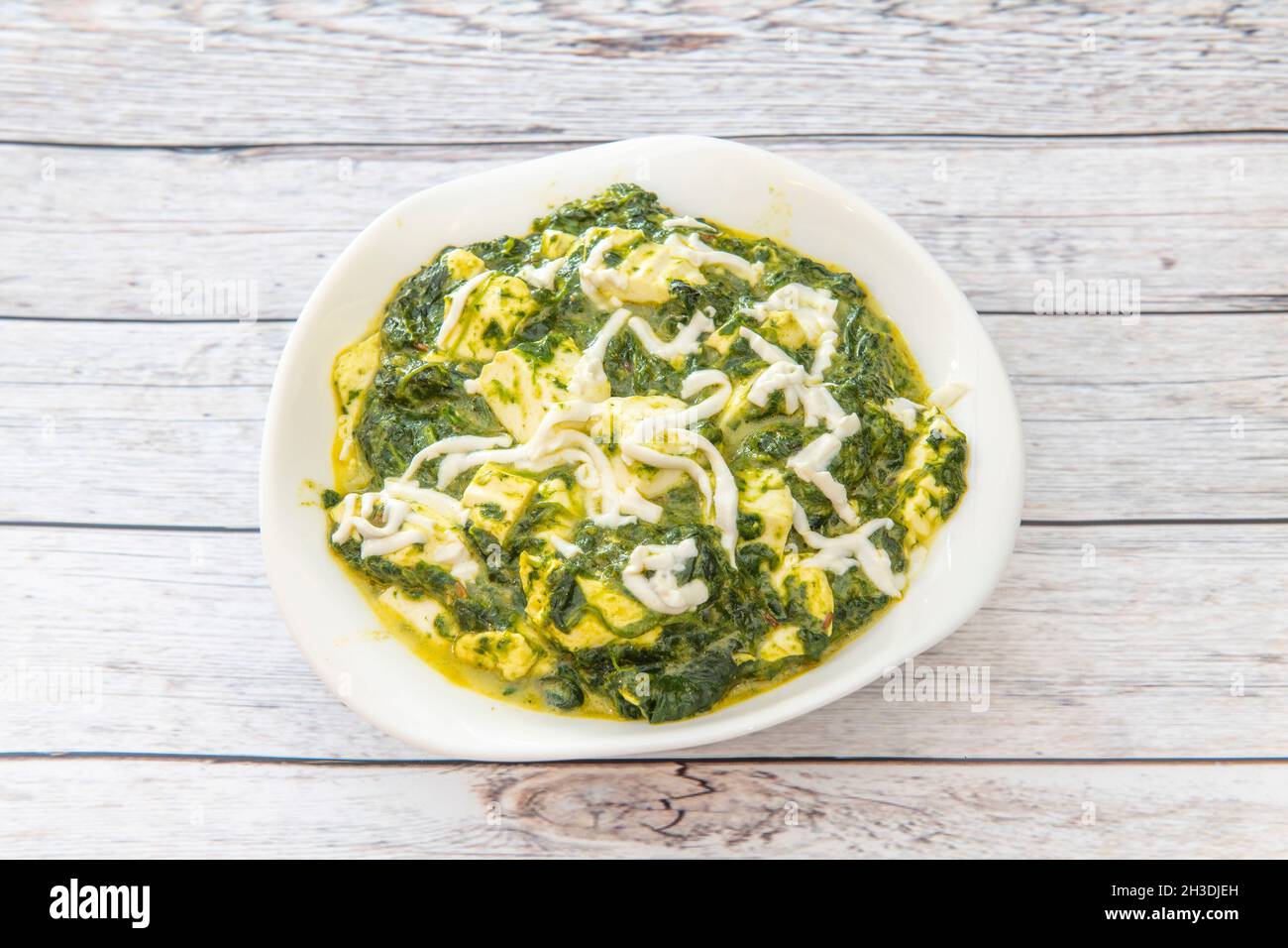 White bowl of palak paneer with spinach and Paneer cheese in curry