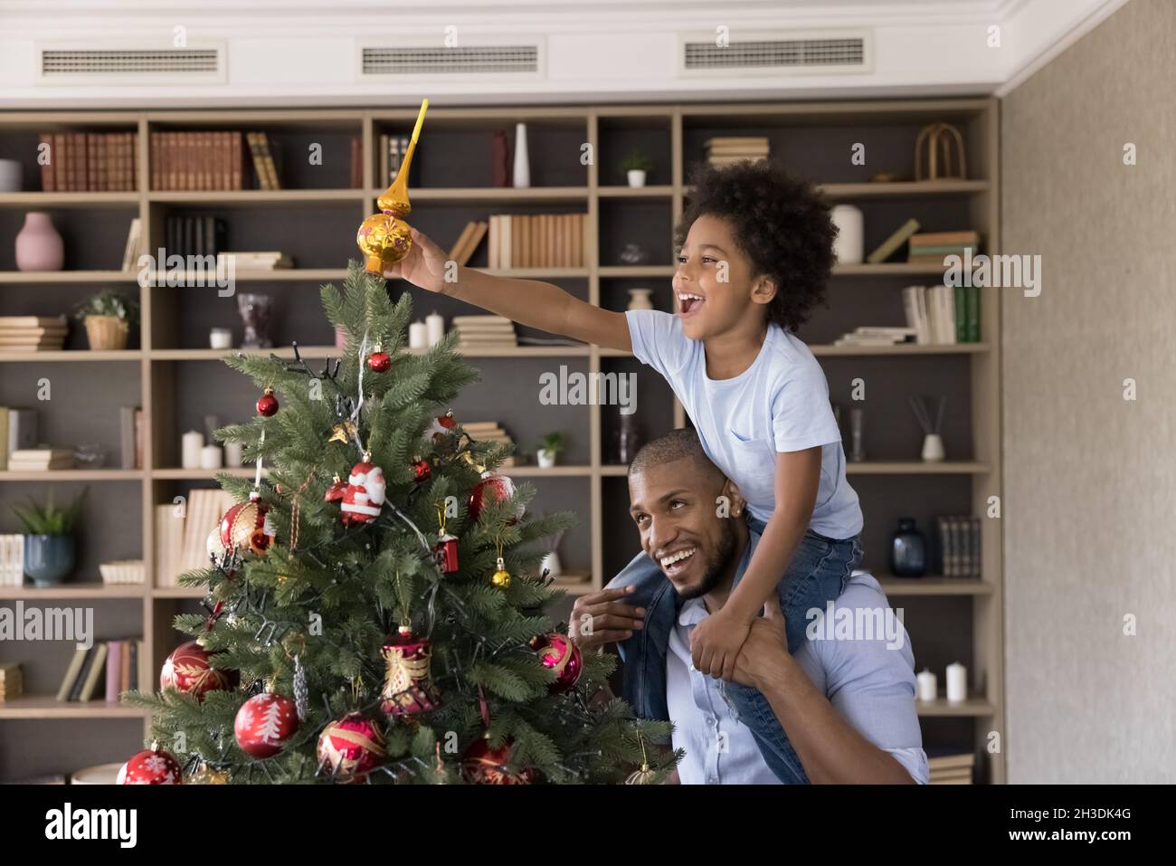 Happy african american family decorating Christmas tree at home. Stock Photo