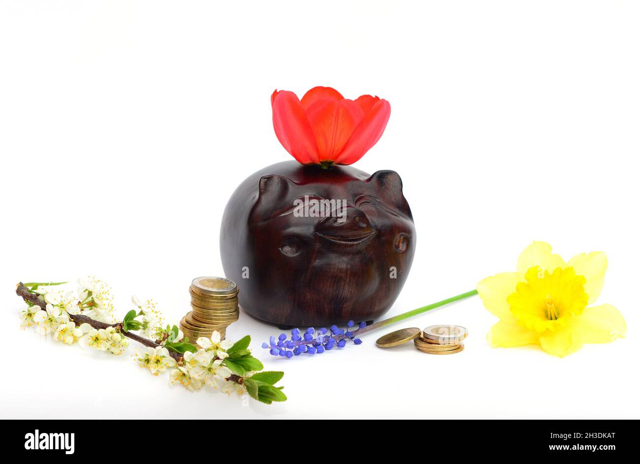 Asian piggybank and money tower with tulip, muscari, narcissus, plump tree flowers symbols of wealth and prosperity.  Piggy bank  concept of savings, Stock Photo