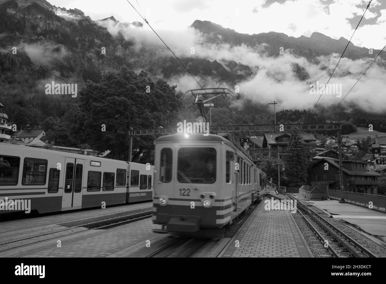 Wengen station busy in the morning with trains up to Kleine Scheigegg: Bernese Oberland, Switzerland.  Black and white version Stock Photo