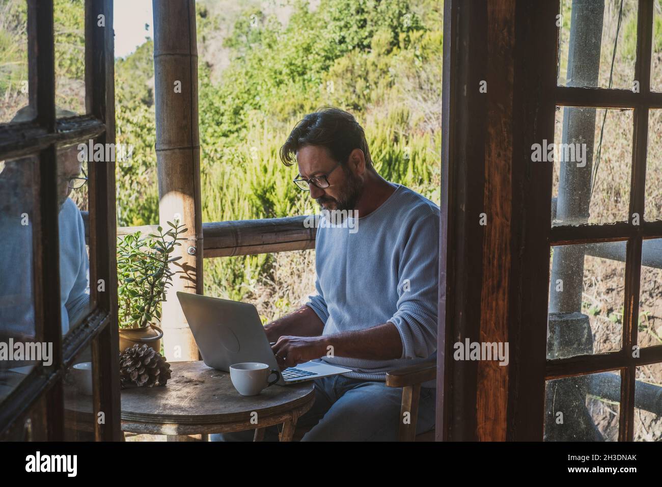 Adult man use laptop computer sitting outdoor at home in alternative office  smart working online job activity. Modern people enjoy wireless connection  Stock Photo - Alamy