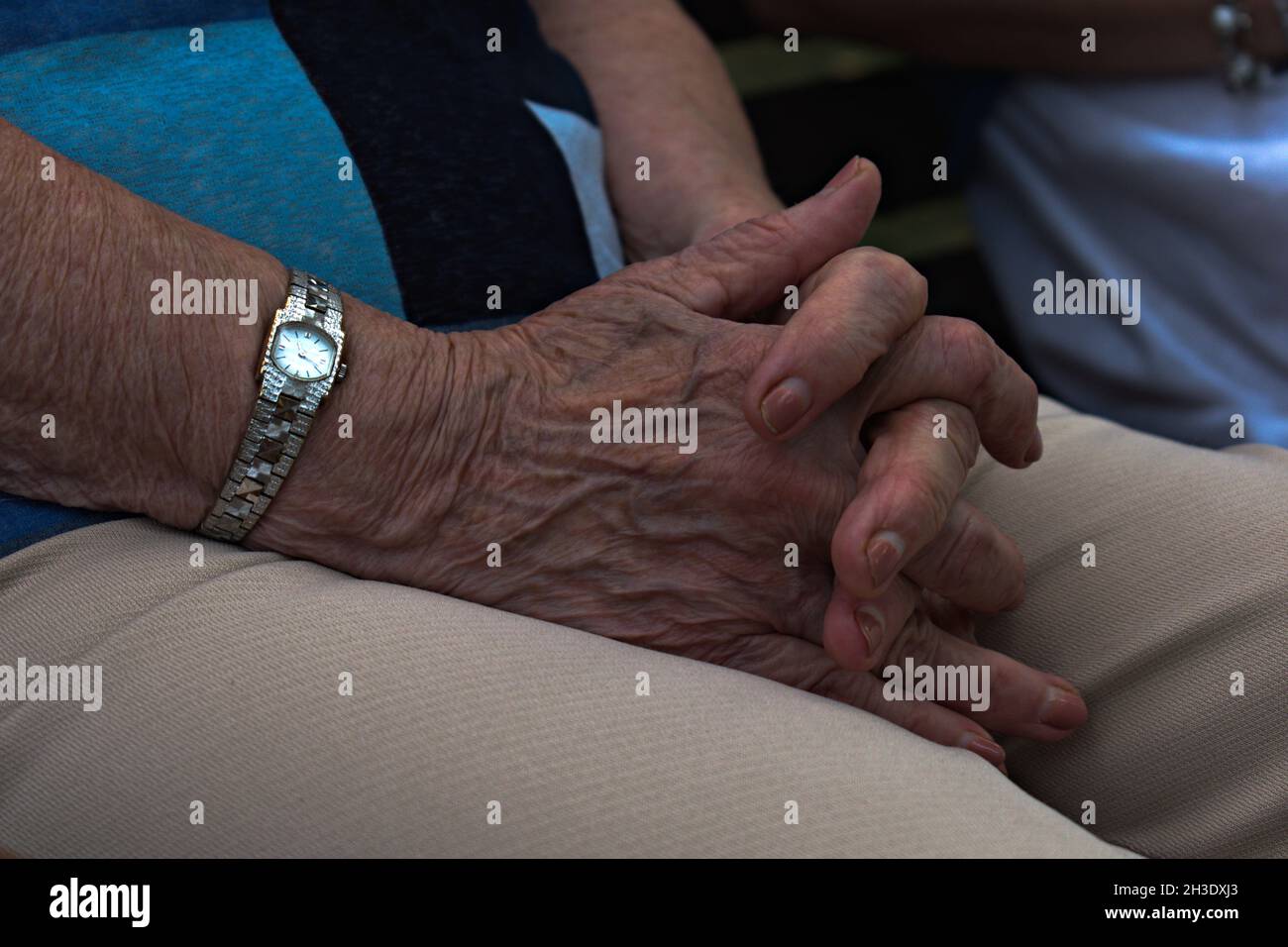 elderly woman hands folded on her knees Stock Photo