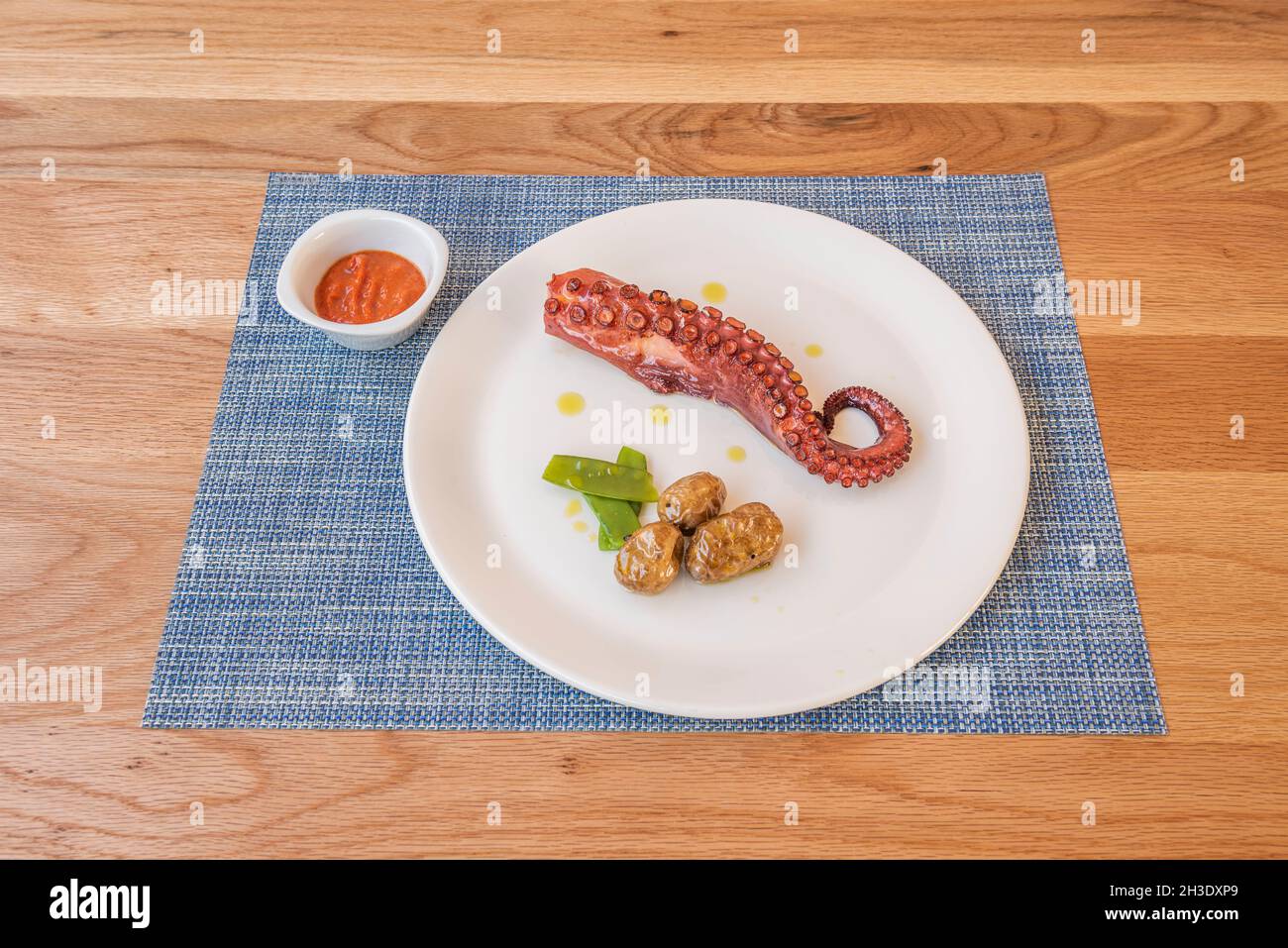 Grilled octopus tentacle with wrinkled potatoes, green beans, virgin olive oil and paprika cream from La Vera Stock Photo