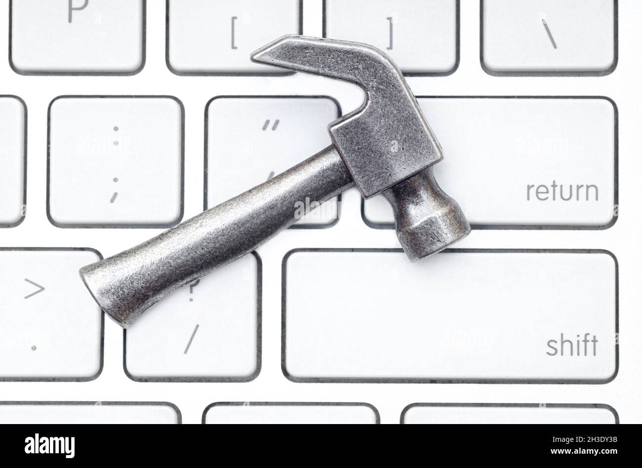 Closeup of a miniature steel hammer on a flat keyboard. Hardware