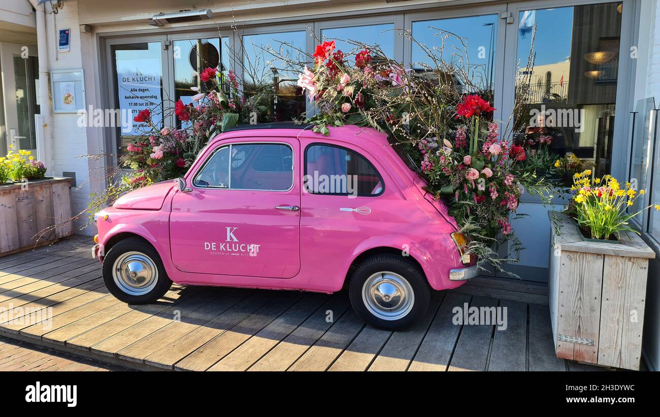 pink Fiat 500 decorated with flowers as decoration in front of a restaurant, Netherlands Stock Photo