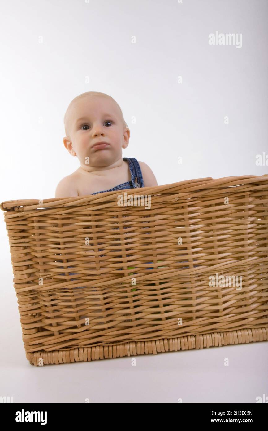 baby sitting in rattan basket Stock Photo