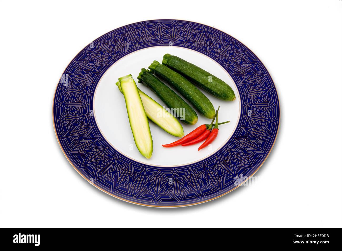 courgette, zucchini (Cucurbita pepo var. giromontiia, Cucurbita pepo subsp. pepo convar. giromontiina), courgettes on a plate, one of them halved Stock Photo