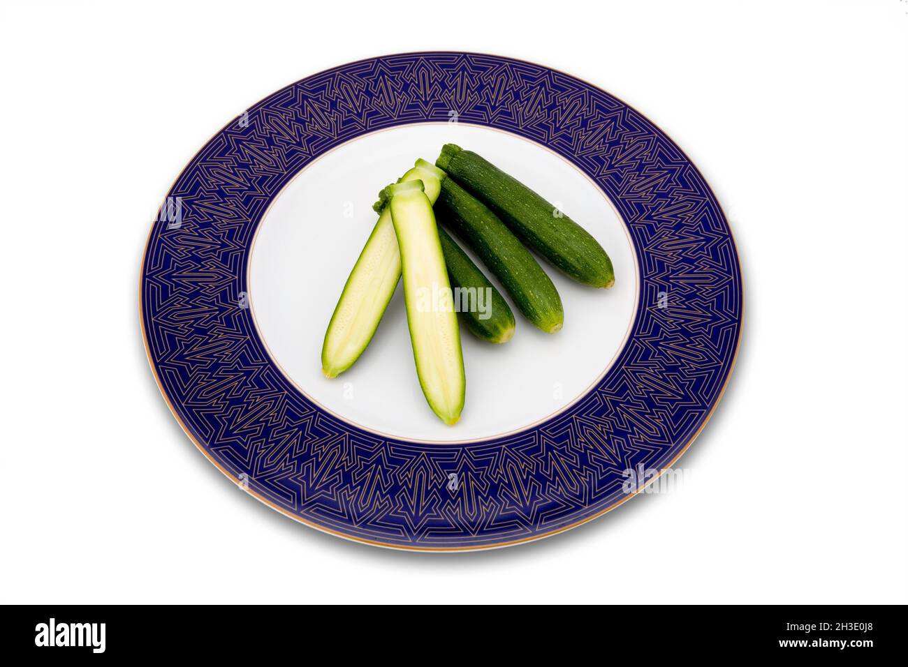 courgette, zucchini (Cucurbita pepo var. giromontiia, Cucurbita pepo subsp. pepo convar. giromontiina), courgettes on a plate, one of them halved Stock Photo