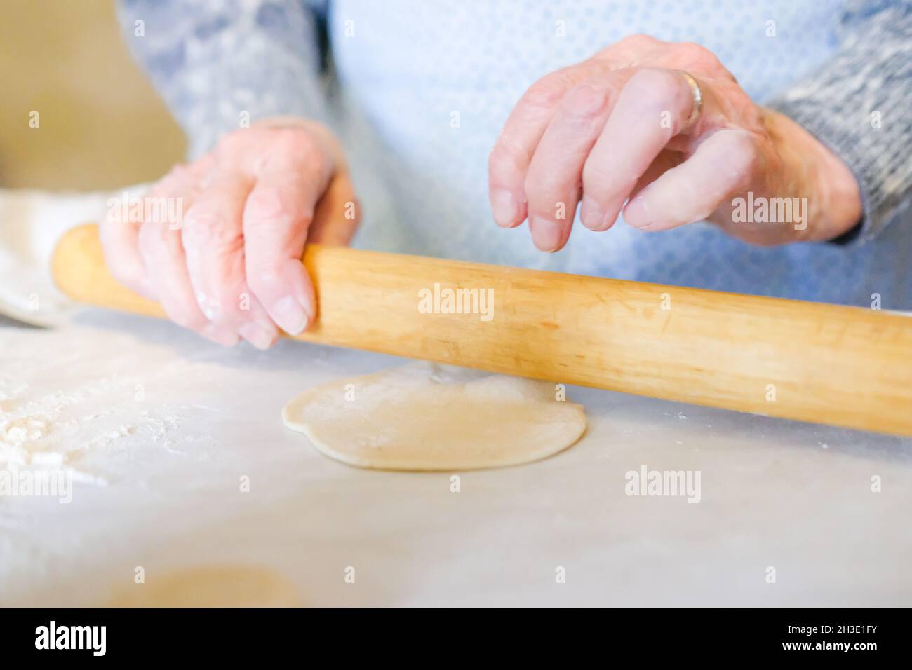 Roll dough. Grandmother rolls out dough for manti Stock Photo