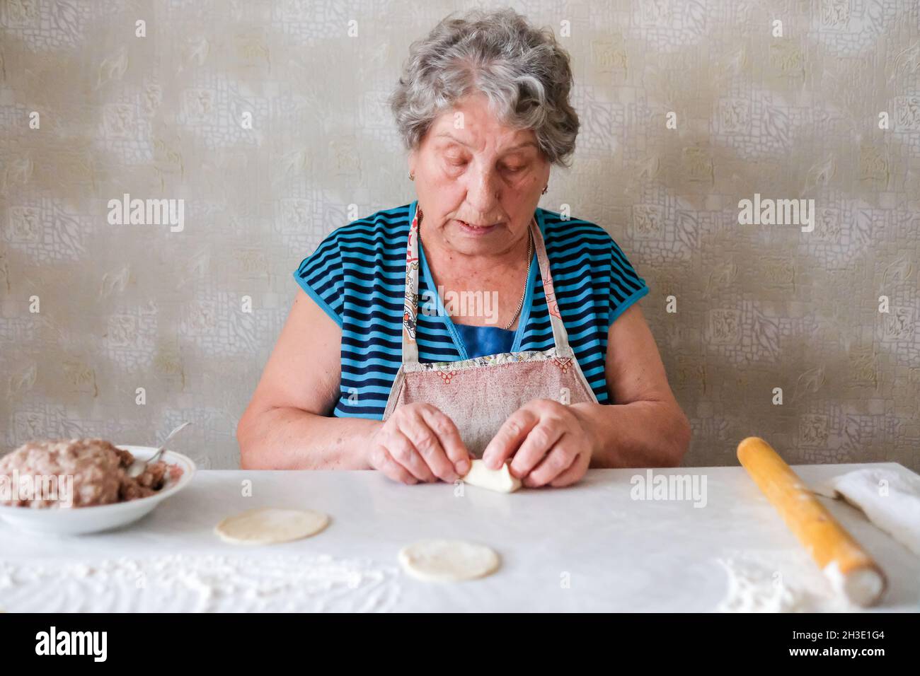 Grandmother makes manti, sculpts a dough dish Stock Photo