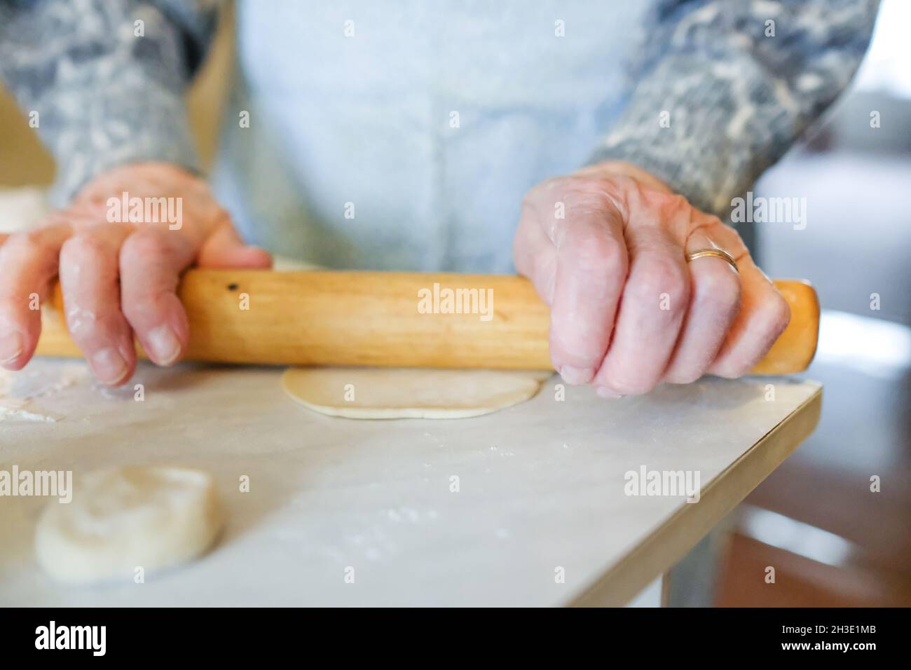 Roll dough. Grandmother rolls out dough for manti Stock Photo