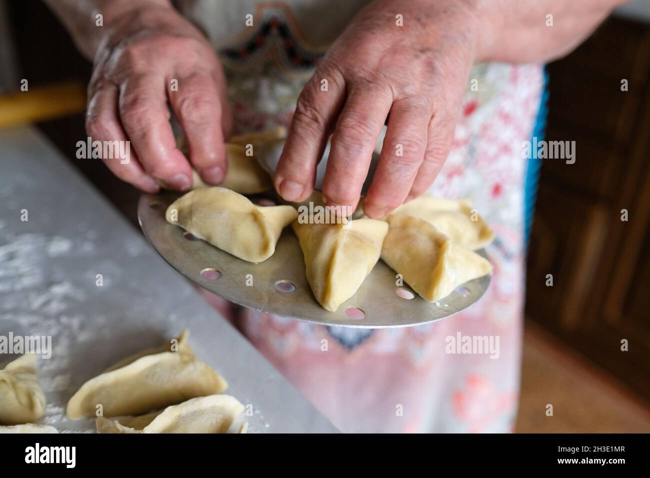Special device for cooking dough. Preparing manti, a dish of dough. Lay down portioned dumplings Stock Photo
