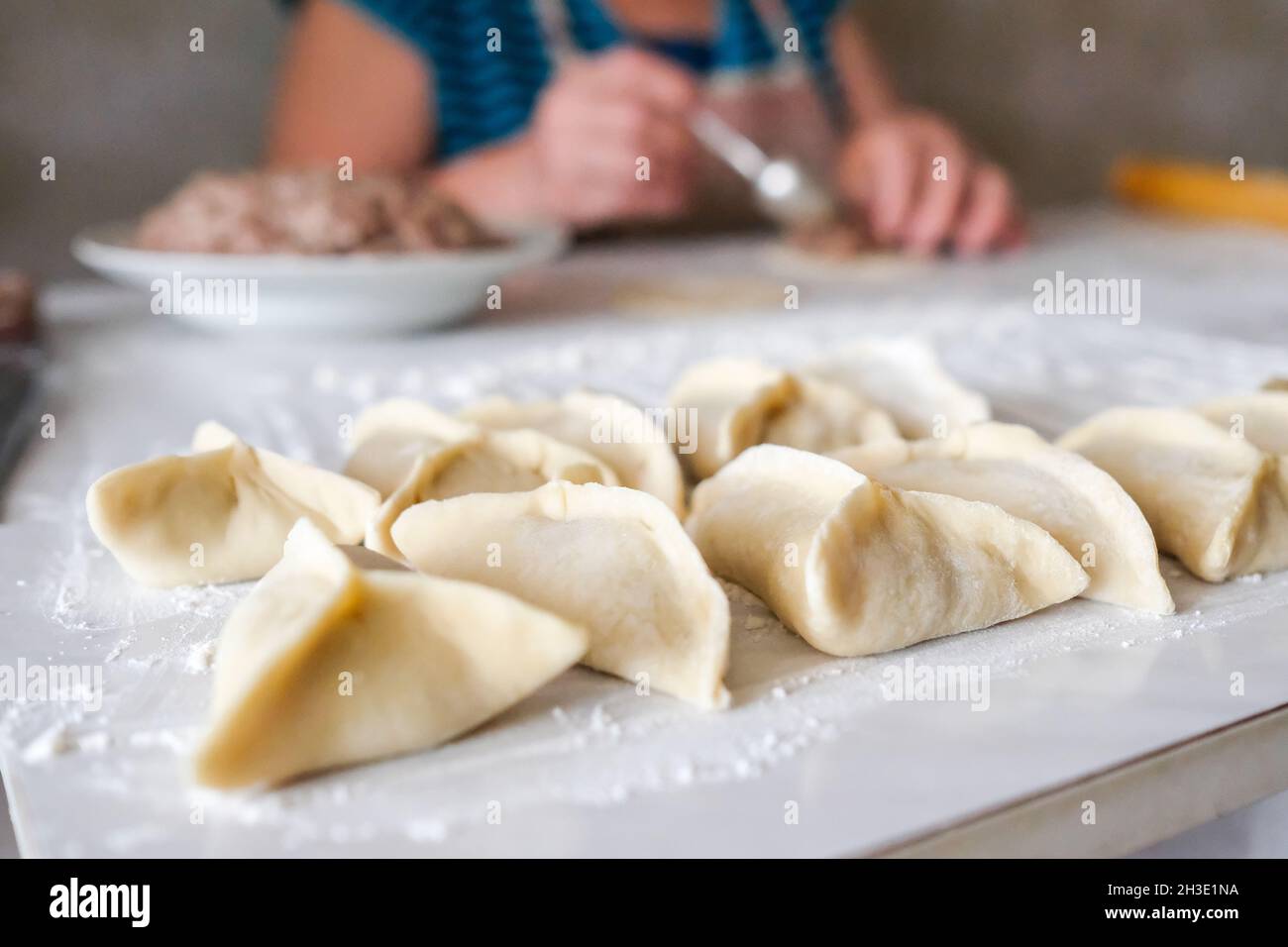 Triangular raw manti lie on the table. Cooking preparation Stock Photo
