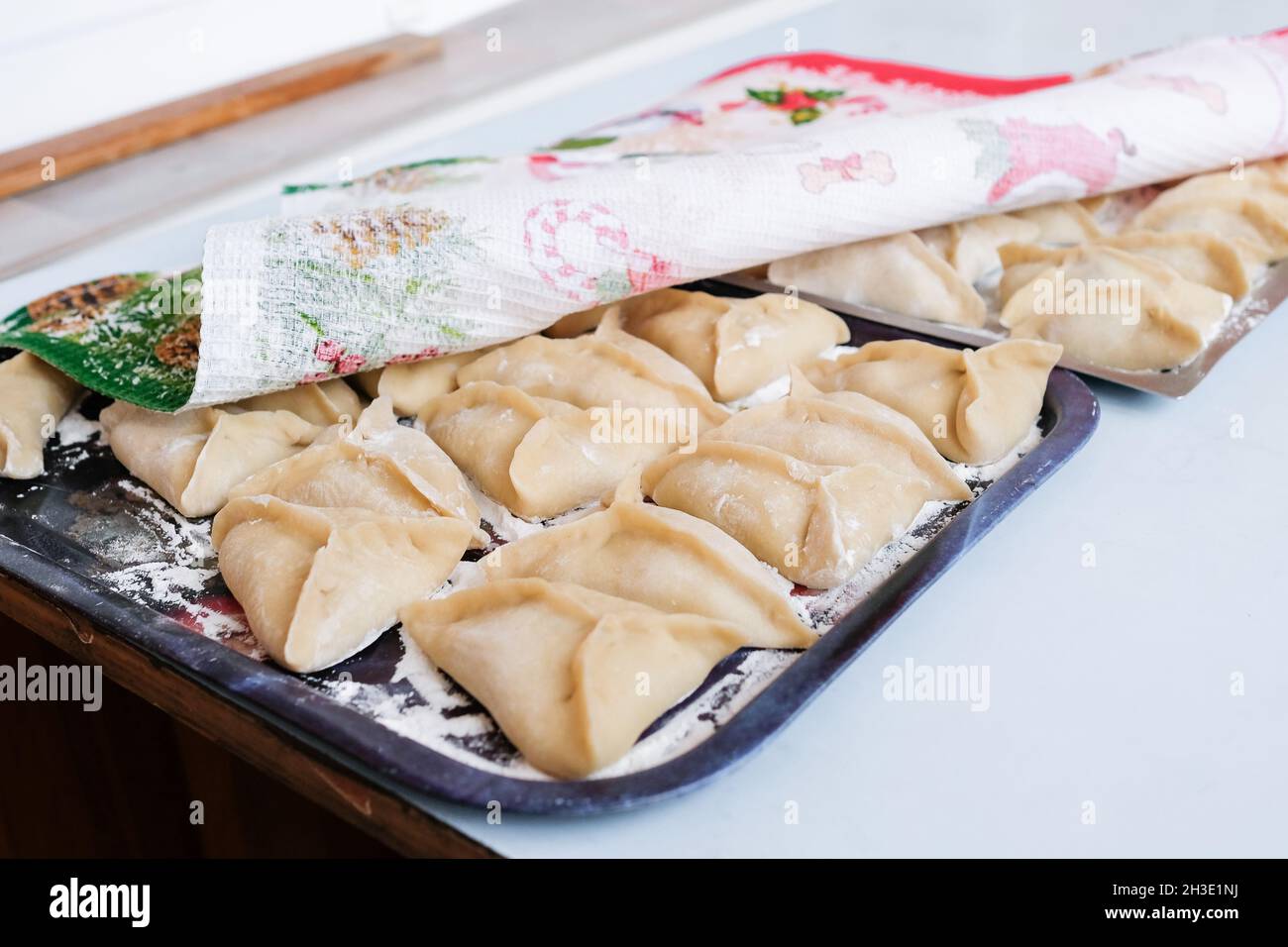 Raw manti on a baking sheet. A dish of dough and minced meat prepared for steaming Stock Photo