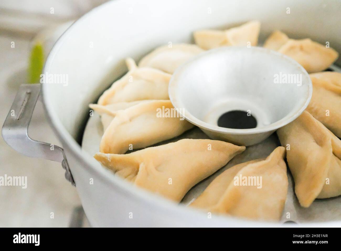 Raw manti put in a slow cooker. A dish of dough and meat is steamed Stock Photo