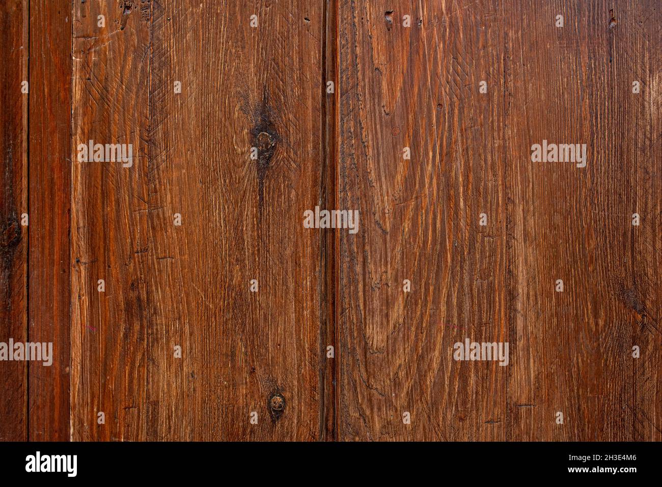 Wood planks with saw marks and dark knots varnished in a dark reddish