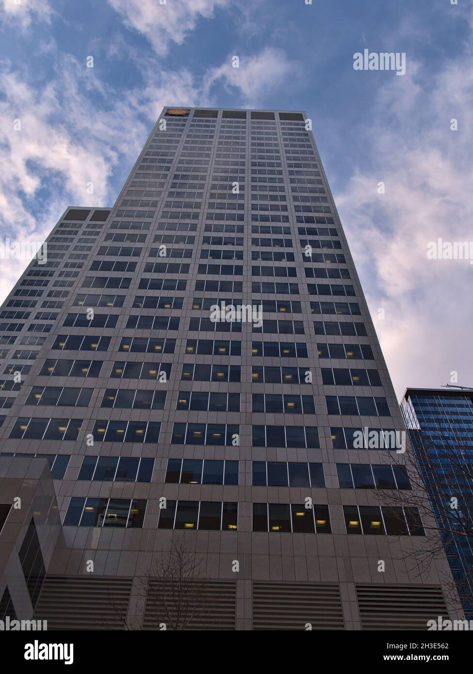 Low angle view of skyscraper Shell Centre (140 m) in Calgary downtown with brand logo on top in the evening light with partly cloudy sky. Stock Photo
