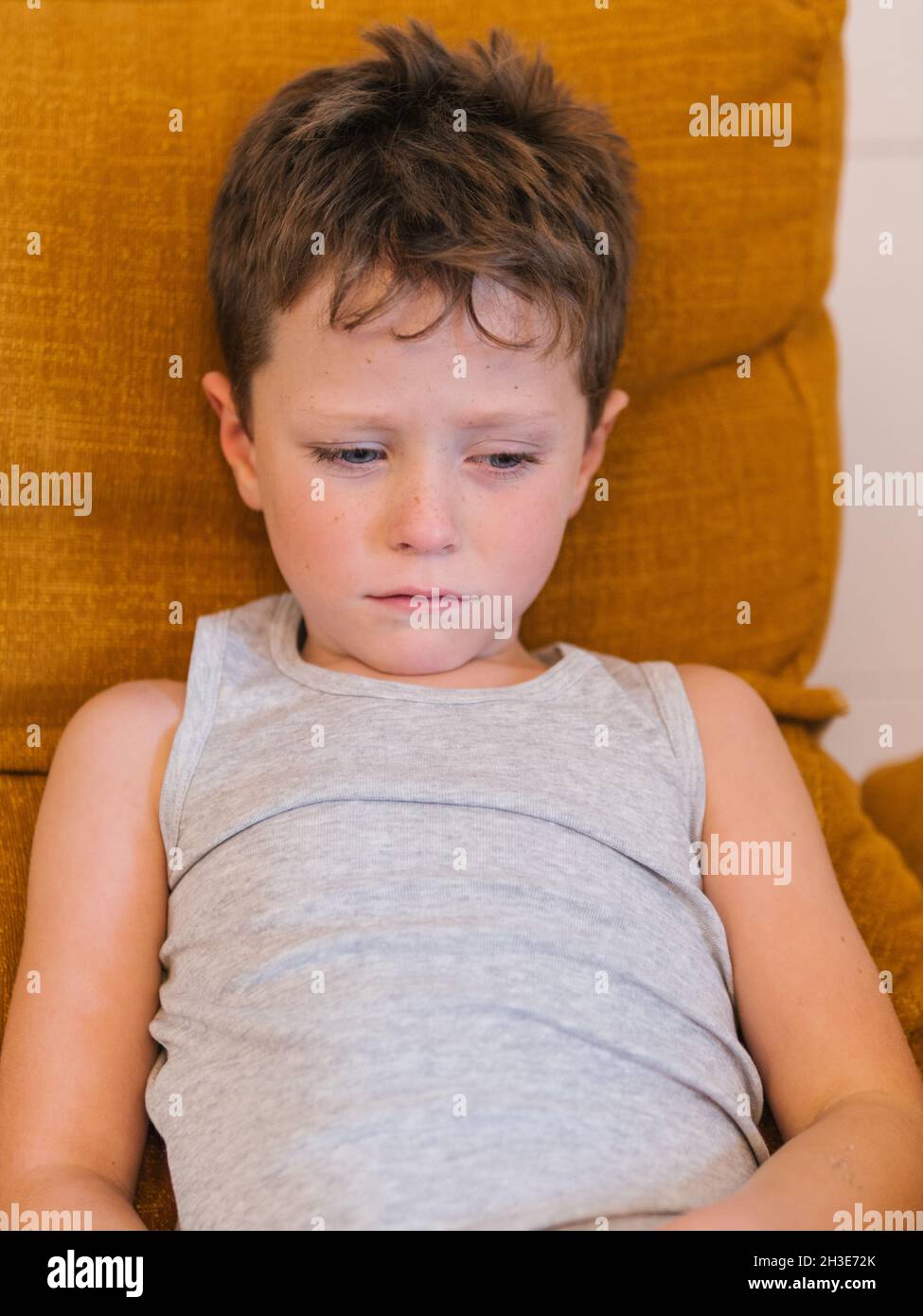 High angle of unhappy ill child having cold and lying on bed at home Stock Photo