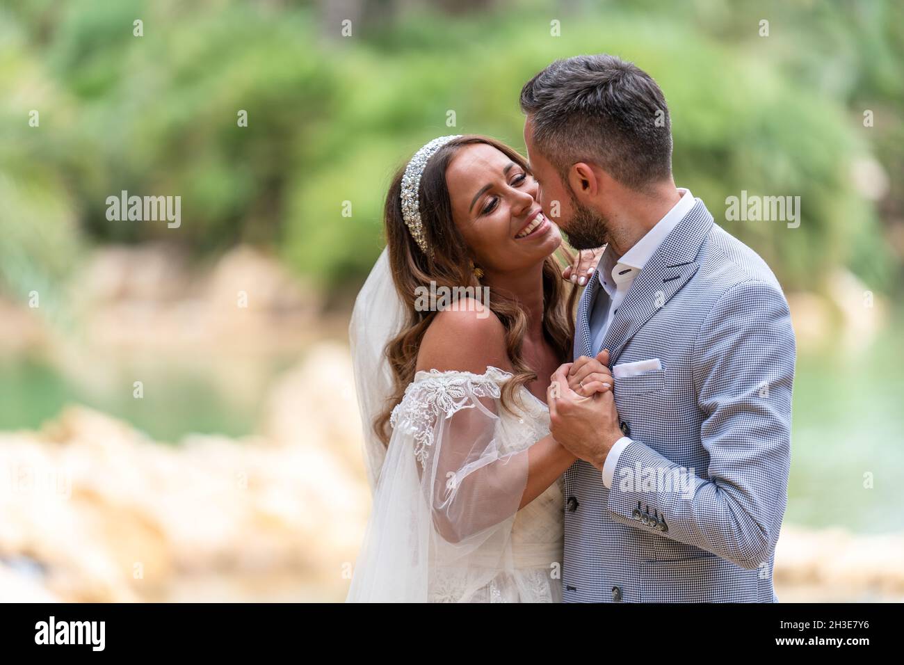 Side view of happy young married couple in wedding clothes standing and ...