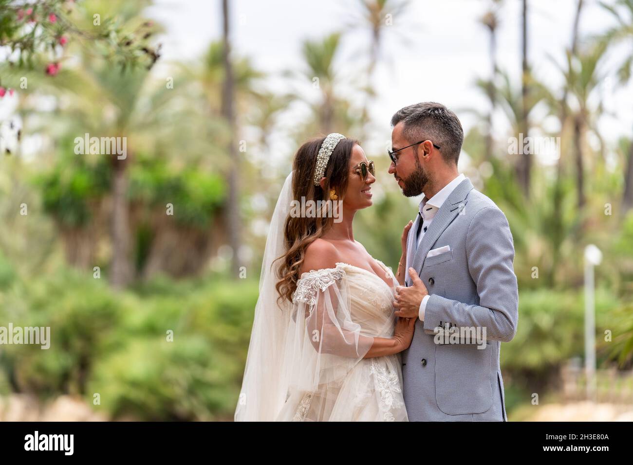 Side view of happy young married couple in wedding clothes standing and ...