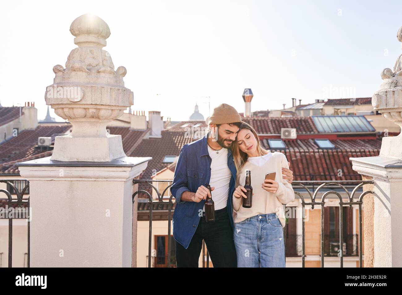 positive young friends using cellphone together while drinking beer