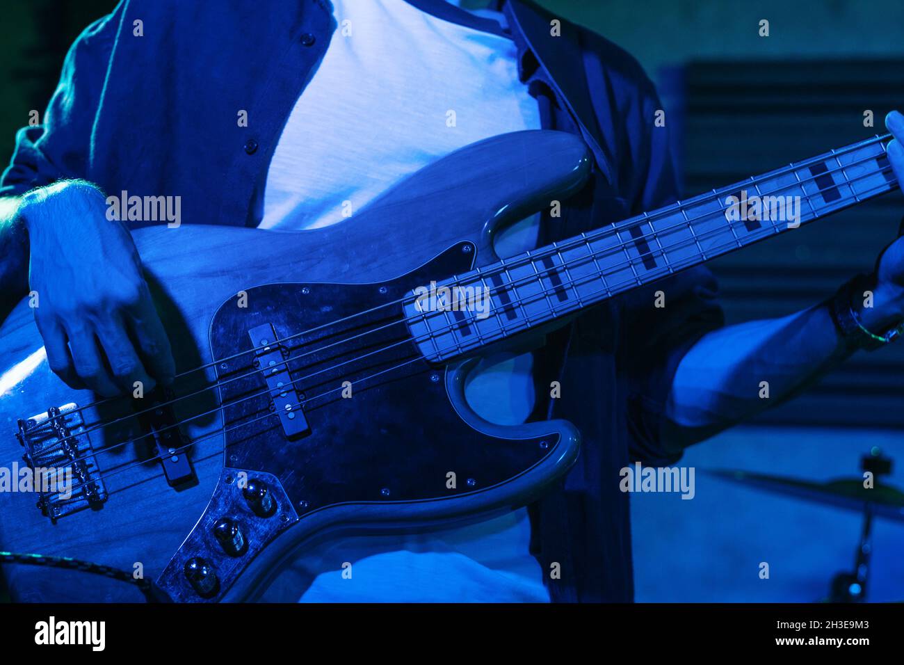 Crop anonymous male guitarist playing electric guitar in club with neon blue lights Stock Photo