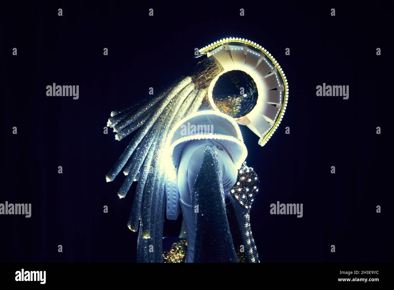 Side view of unrecognizable person in futuristic LED suit of space character with glowing neon lights on black background in studio Stock Photo