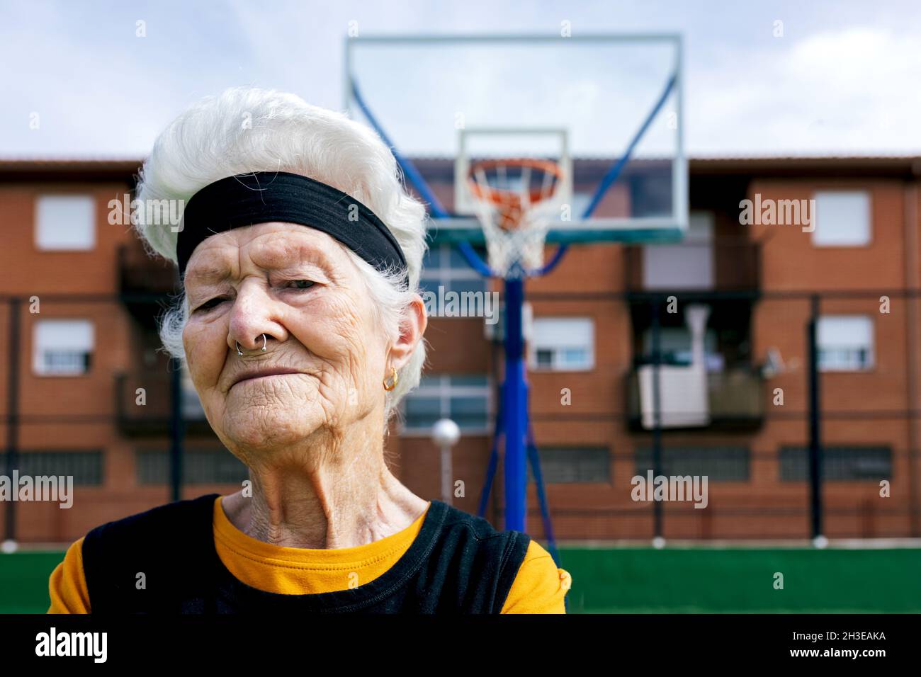 Confident mature female in sportswear with pierced nose looking at camera while standing on sports ground during training on street Stock Photo