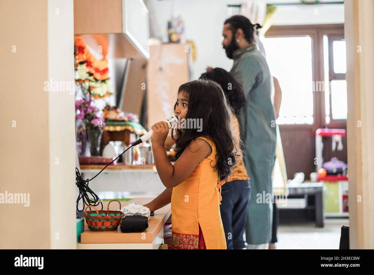 Indian family celebrating Diwali or hindu festival at home - Focus on girl playing with microphone Stock Photo