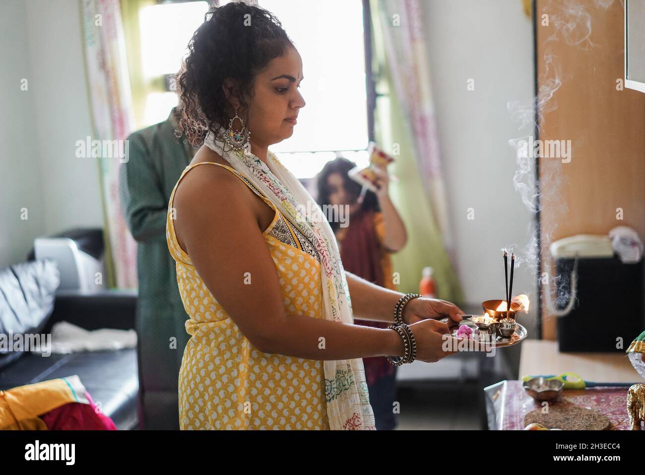 Indian family celebrating Diwali or hindu festival at home - Focus on mother hands holding offerings Stock Photo