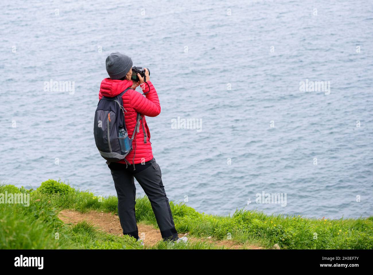 Woman photographer taking pictures from a coastal path Stock Photo