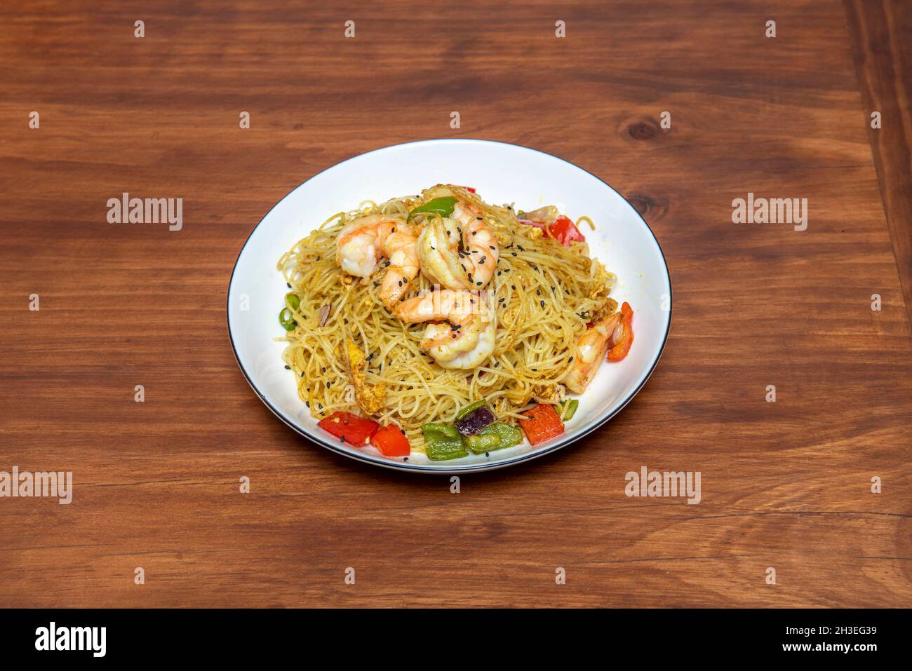 Chinese rice noodles with prawns and vegetables sautéed in the wok and