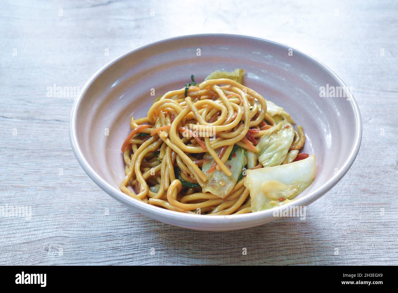 spicy stir fried vegetarian yakisoba Japanese noodles with cabbage and basil leaf on bowl Stock