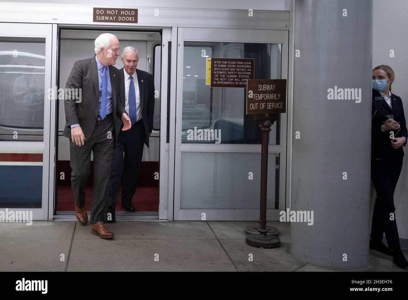 A Senate Page watches from afar as Senators John Cornyn, a Republican from Texas, and Ron Johnson, a Republican from Wisconsin, exit a Senate Subway car ahead of a vote on Capitol Hill in Washington, DC, U.S., on Wednesday, Oct. 27, 2021. Senate Democrats released the details of a proposed levy on billionaires, a new and logistically risky approach to taxation that lawmakers hope will help fund the White House's social spending aimed at low and middle-income Americans. (Photographer: Tom Brenner/Pool/Sipa USA) Credit: Sipa USA/Alamy Live News Stock Photo