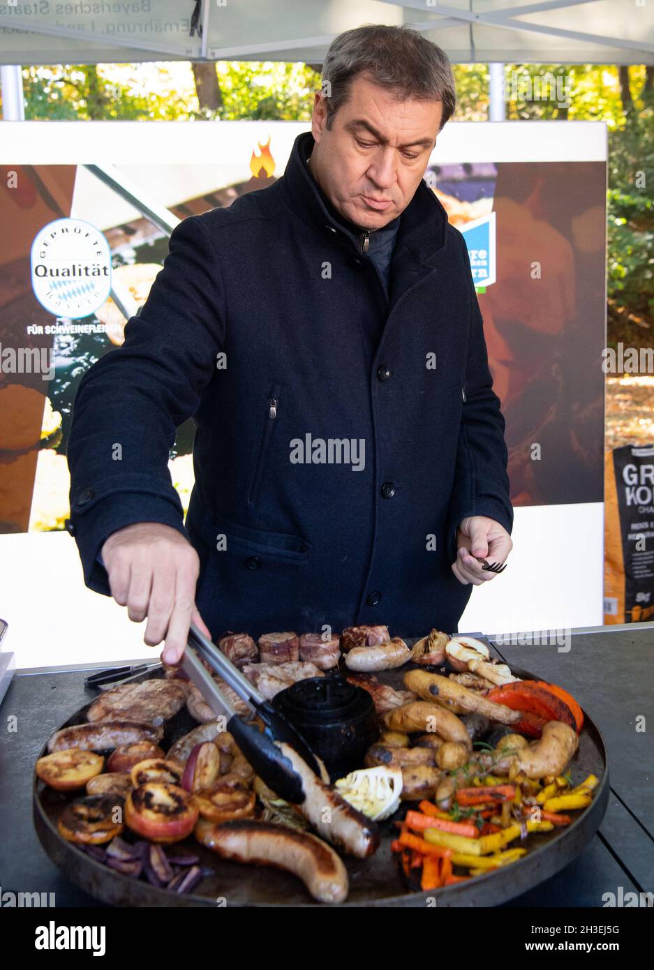 Munich, Germany. 28th Oct, 2021. Markus Söder (CSU), Prime Minister of  Bavaria, stands at a grill and turns the grilled meat as part of the barbecue  campaign "Grillen geht immer! Credit: Sven